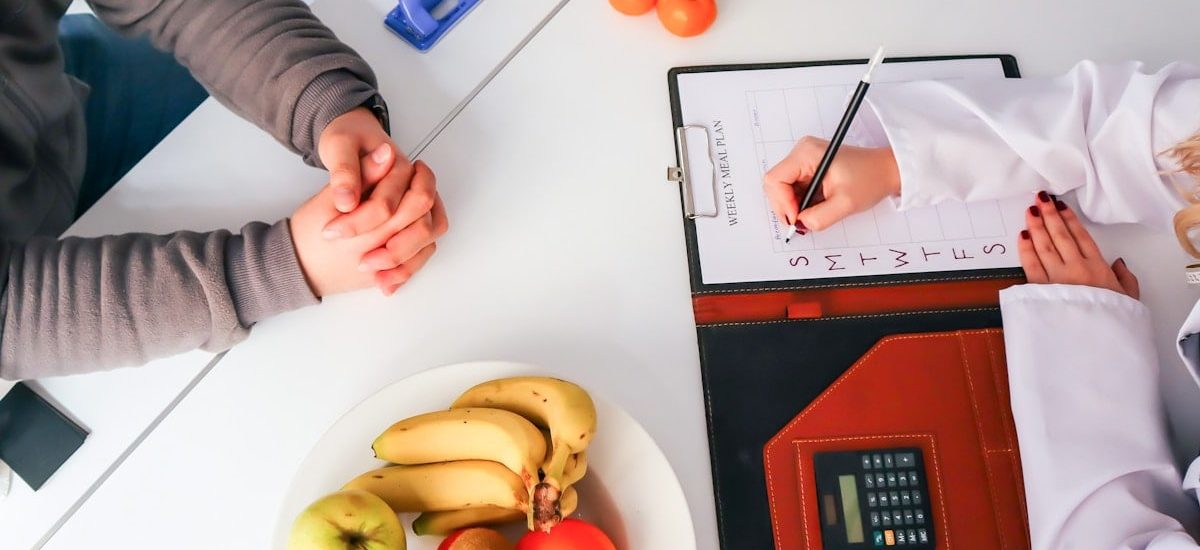 a couple of people sitting at a table with a plate of fruit