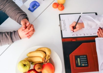 a couple of people sitting at a table with a plate of fruit